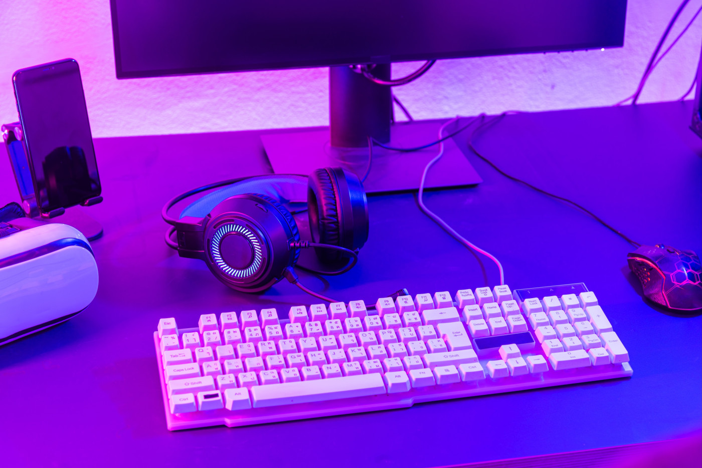 Desktop set up for working on computer simulation and gaming with headphones, mouse, Augmented Reality glasses and more.