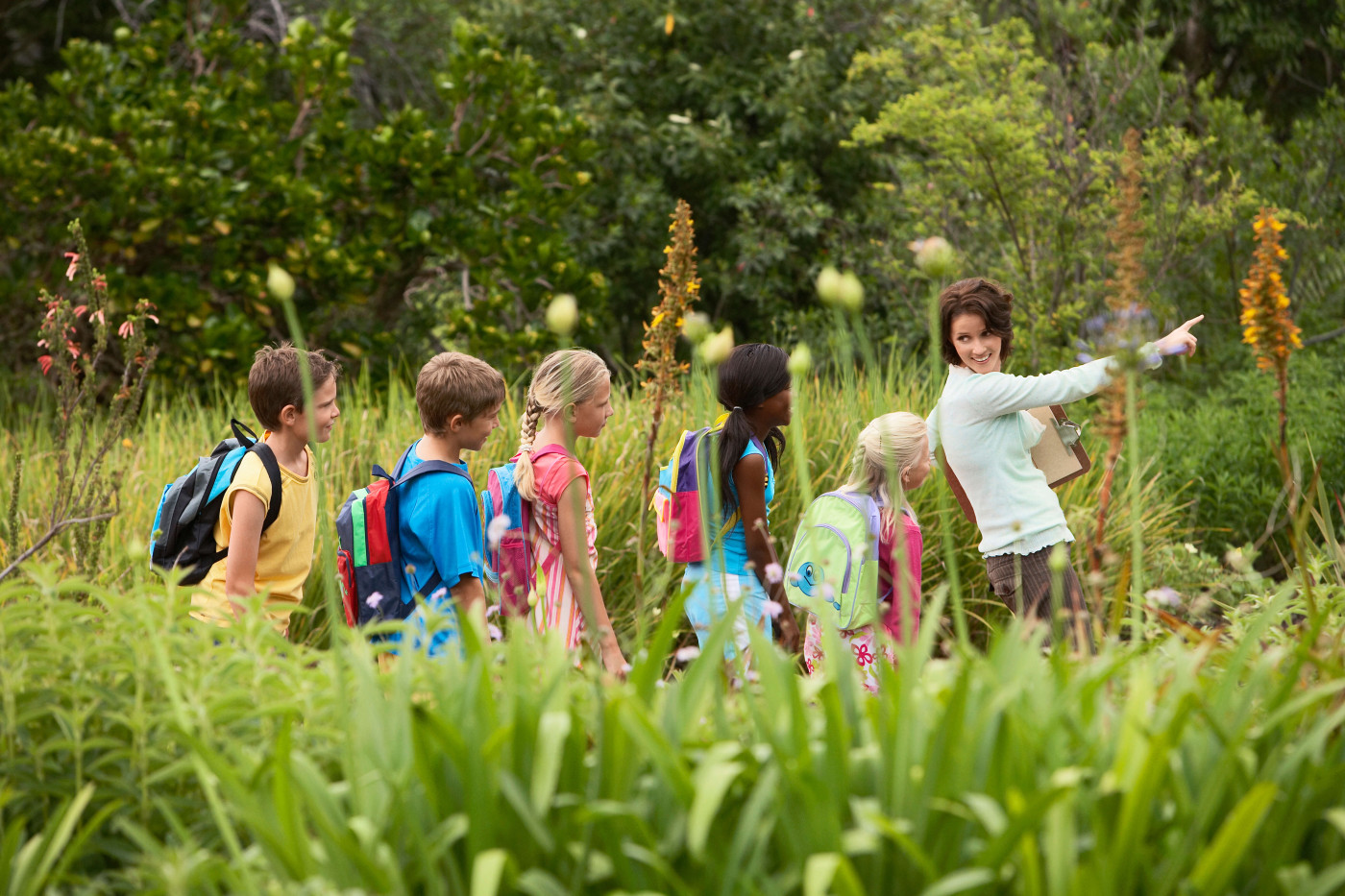 Students walking with their teacher through a field