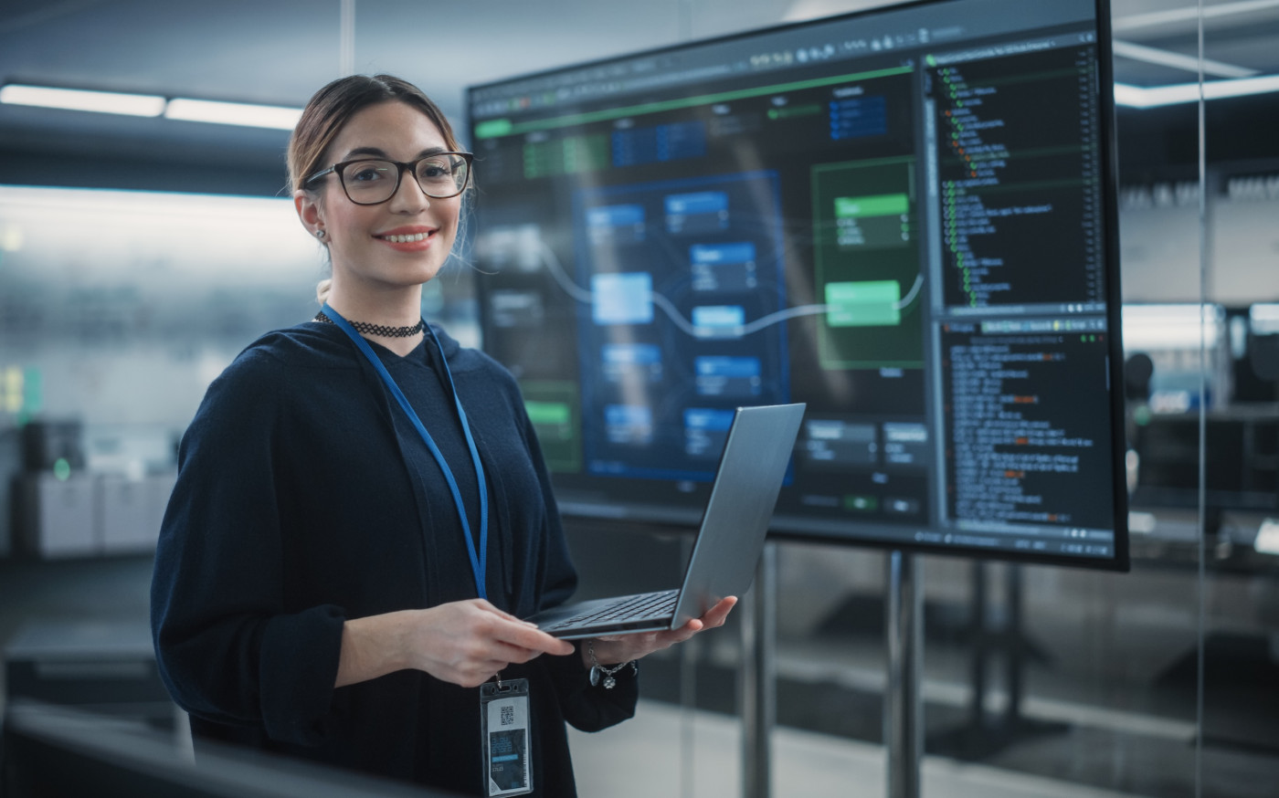 Student standing in front of large smart board with laptop, developing artificial intelligence