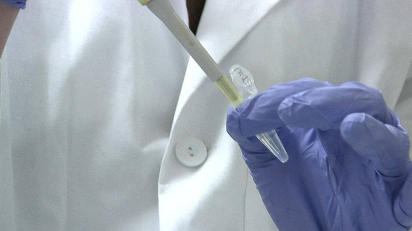 Person in lab coat with a sample