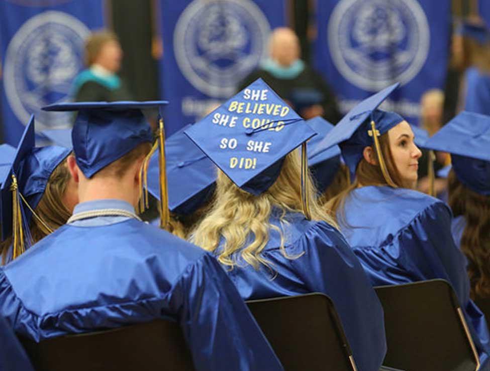 Back of graduates featuring cap saying, "She believed she could, so she did."