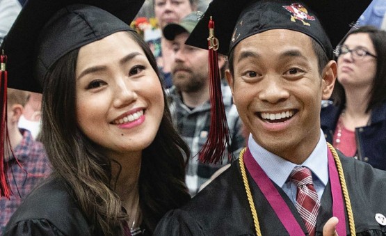 Two graduates smiling together at graduation ceremony