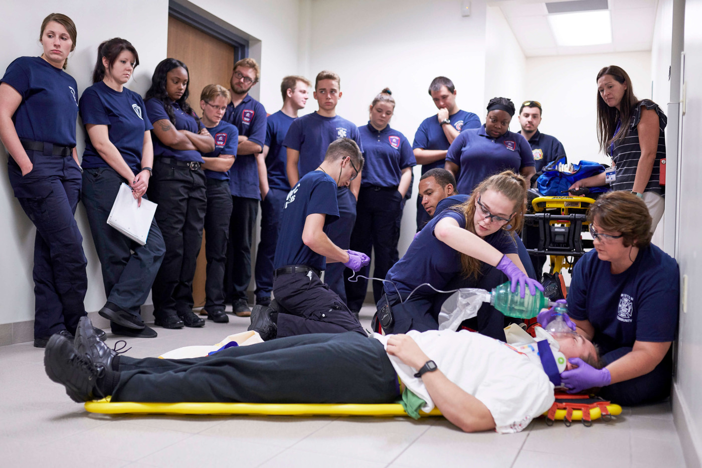 Students in class watch as instructors demonstrate how to provide life-saving support to a patient.