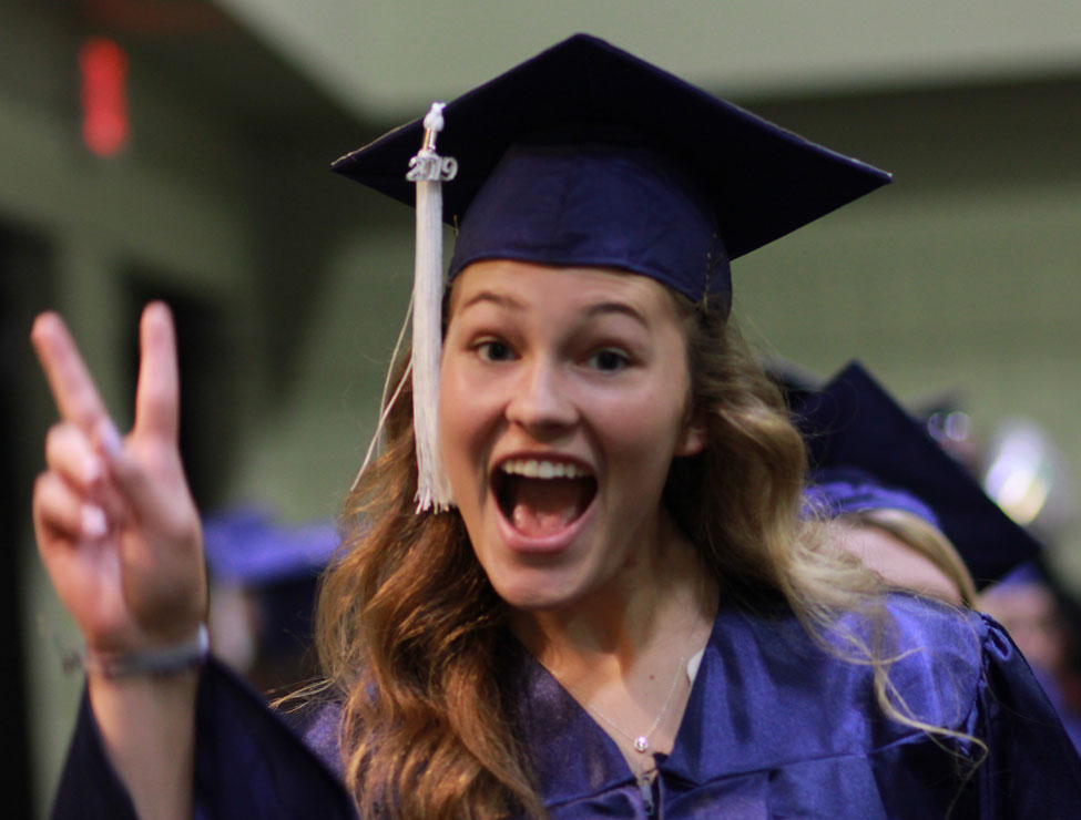 Graduate holding up piece sign with fingers