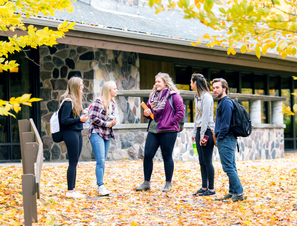 Students chatting outside campus building in the fall