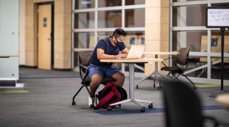 Student wearing mask while studying on campus