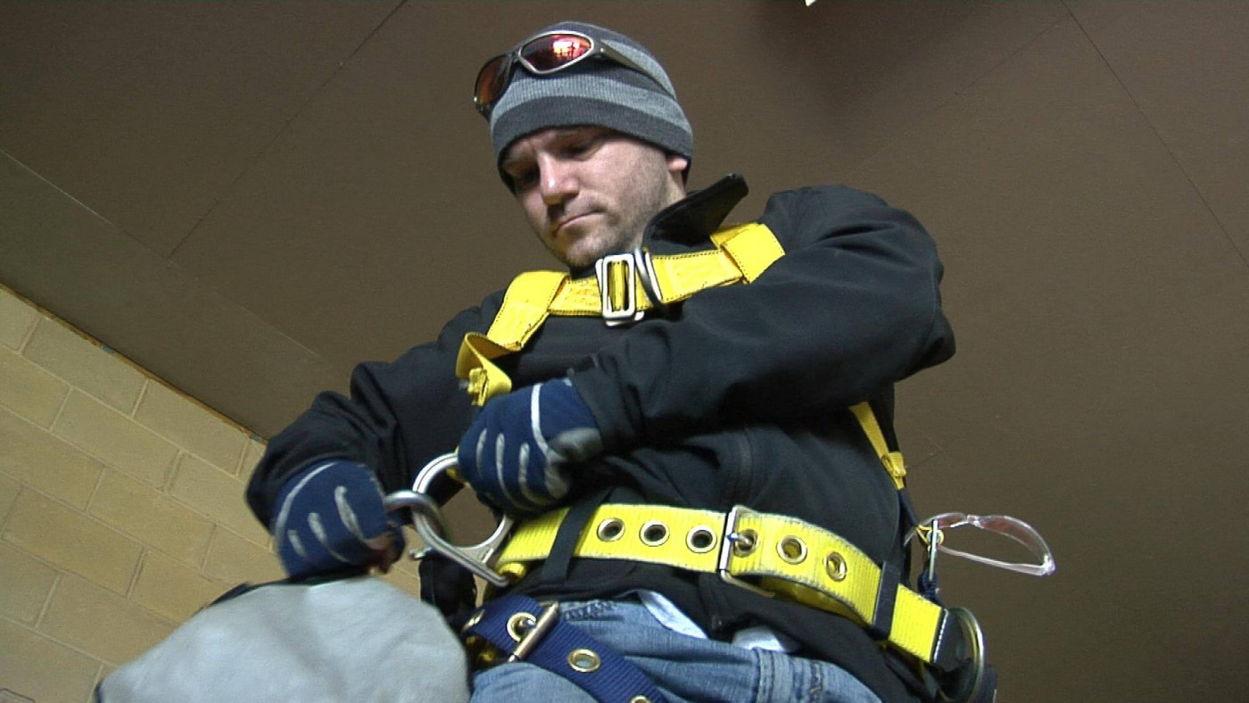 Wind tower climber putting on harness for safety