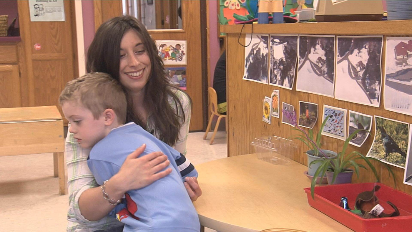 teacher comforting a child in an early childhood care setting