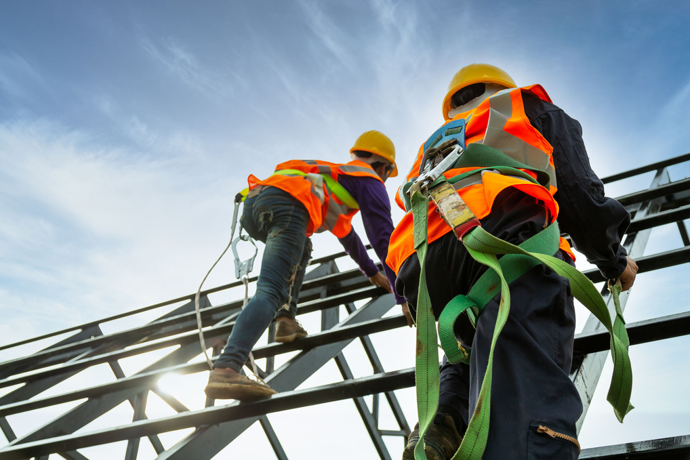 Safety Engineering Technology workers climbing up a scaffold with harnesses.
