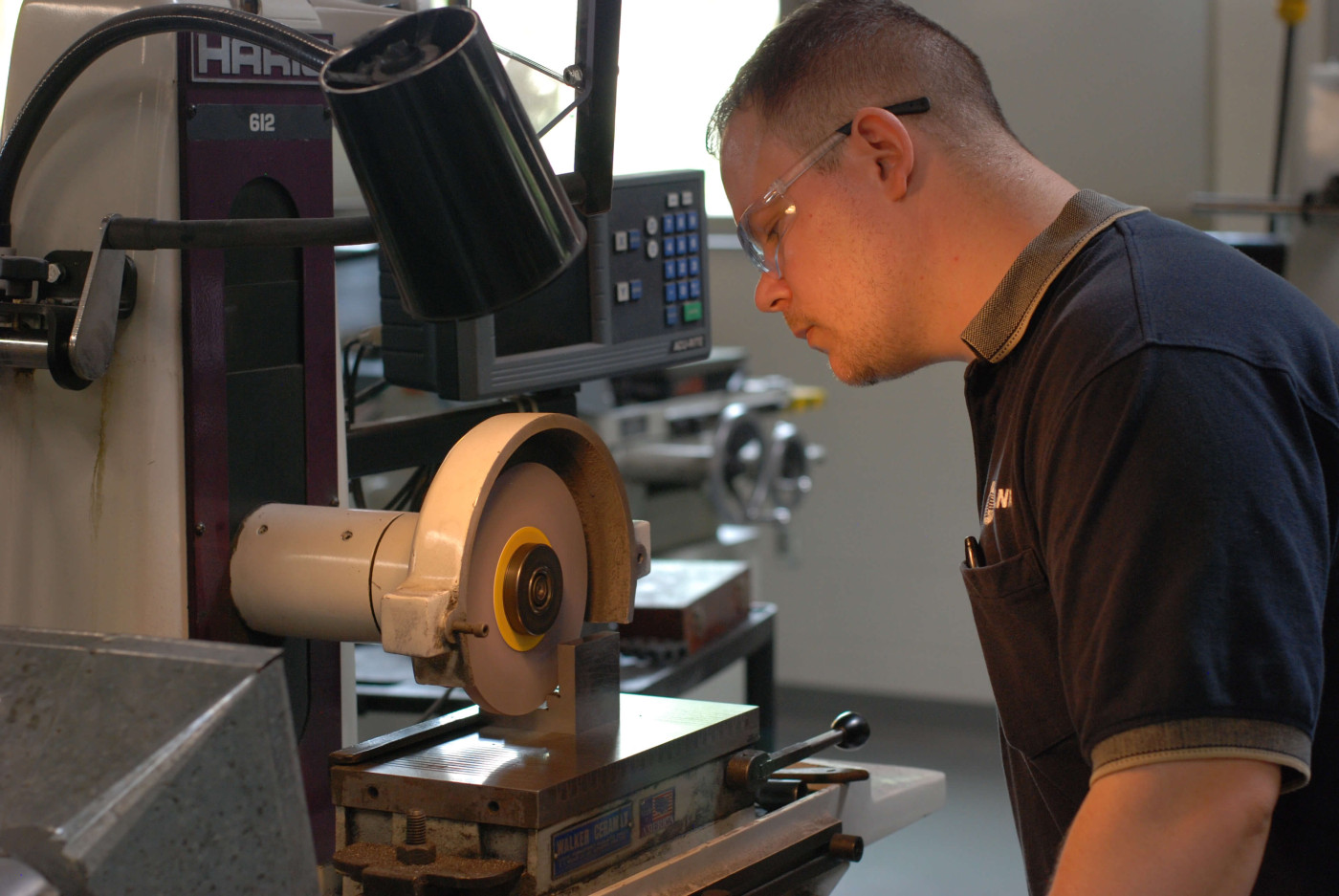 Man standing in front of a machine tool obsering the machining of a part