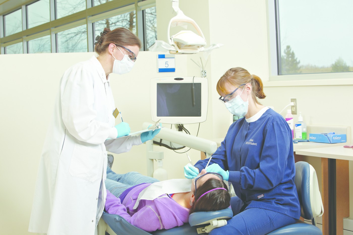 Dental hygienist and dentist with patient