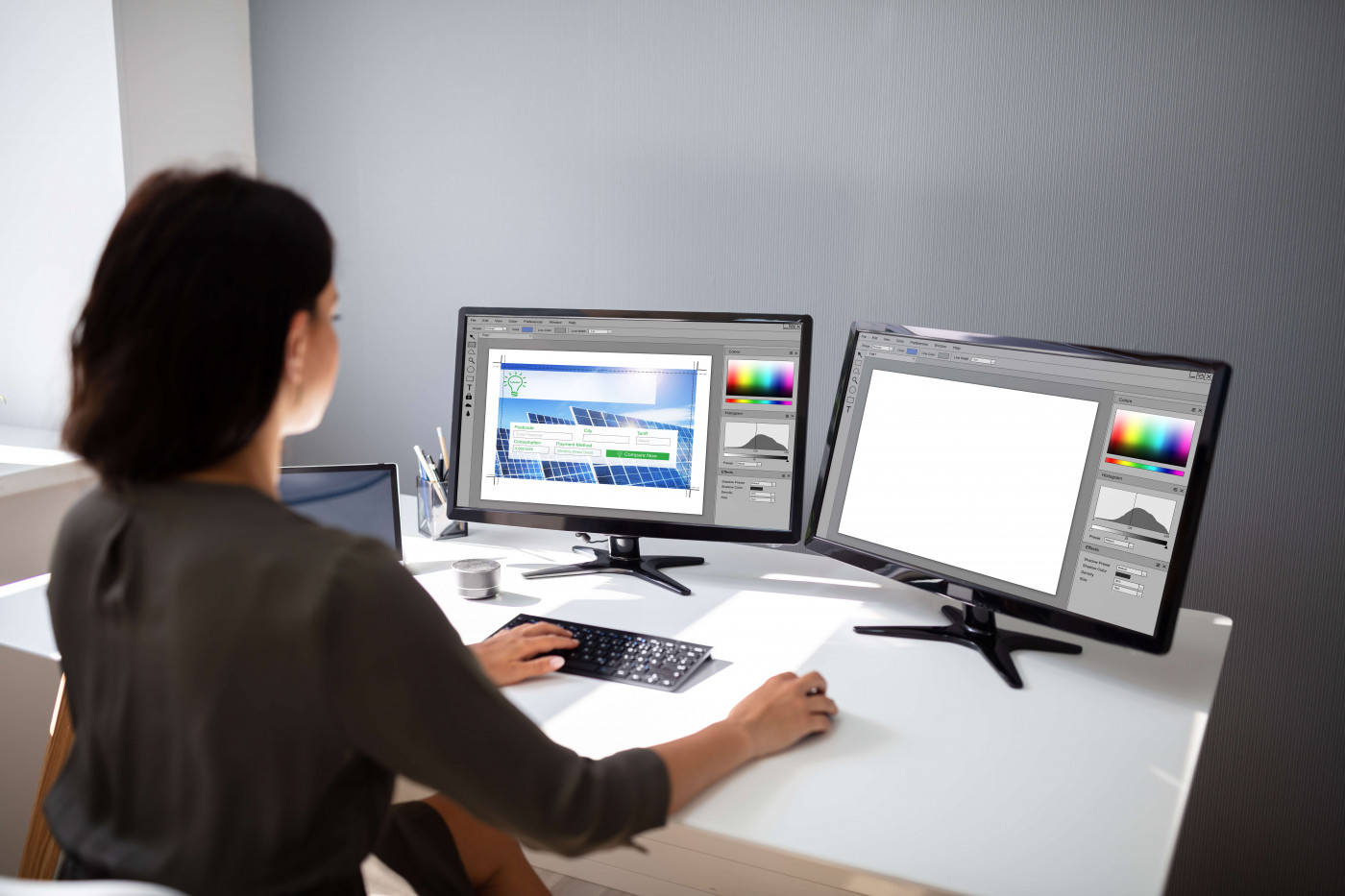 web designer sitting in front of two monitors 